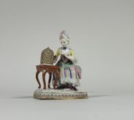 A Meissen porcelain figure, late 19th century, of a seated lady feeding a bird in a cage, emblematic