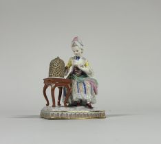 A Meissen porcelain figure, late 19th century, of a seated lady feeding a bird in a cage, emblematic