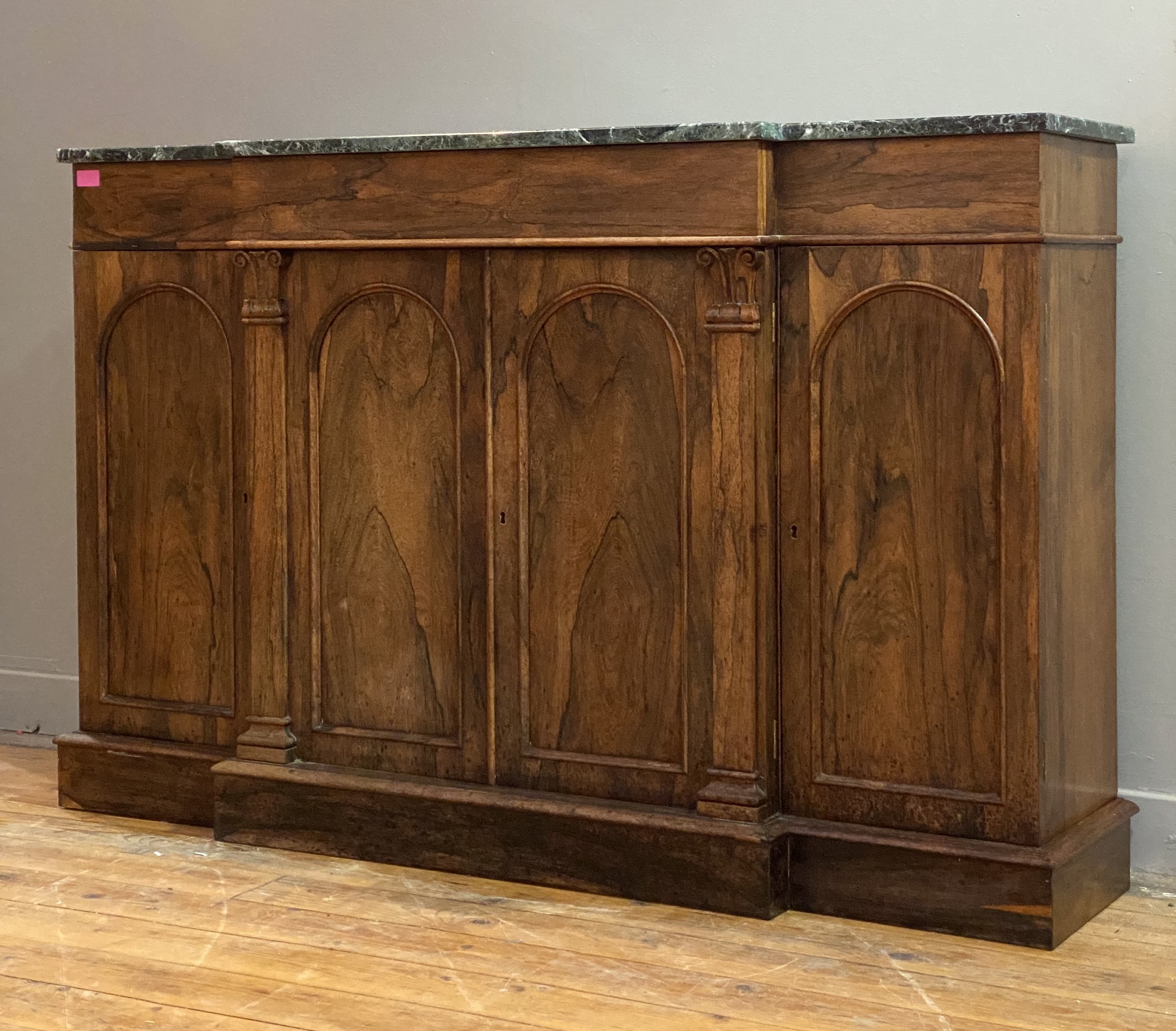 A shallow William IV rosewood breakfront credenza, the (later) green serpentine marble top above a