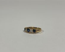 An 18ct gold five-stone sapphire and diamond ring, the three graduated round-cut sapphires spaced by