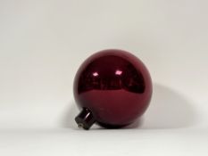 A cranberry glass witches ball, of characteristic form. Diameter c. 24cm