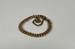 A yellow metal curblink bracelet, unmarked, suspending a small Asian yellow metal coin or medallion,