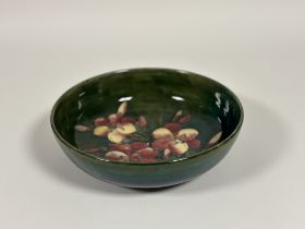 A large William Moorcroft pottery bowl, in the Lily pattern, tubelined and painted against a green