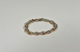 A yellow metal chainlink bracelet set with seed pearls and turquoise cabochons, with safety chain,