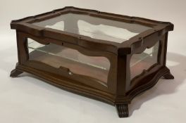 A late Victorian mahogany table-top display case of serpentine outline, the glazed hinged lid and