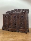 An Anglo-Indian carved teak side cabinet, mid-19th century, the raised and arched back profusely