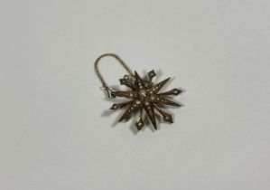 A Victorian 9ct gold starburst brooch set with seed pearls, stamped mark and with safety chain.