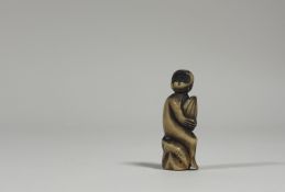 A Japanese carved bone netsuke, 19th century, modelled as a monkey holding a giant chestnut.