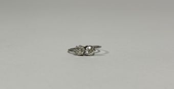 A two stone diamond crossover ring, the two slightly graduated round brilliant-cut stones claw-set