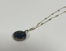 An unusual sapphire locket, c. 1900, the circular case pave-set with round-cut sapphires of