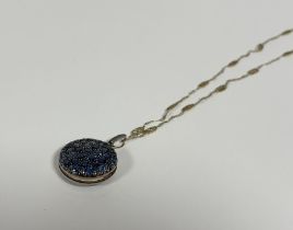 An unusual sapphire locket, c. 1900, the circular case pave-set with round-cut sapphires of