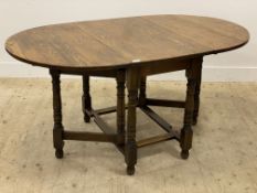 An oak drop leaf dining table, early 20th century, the oval top raised on turned and block gate-