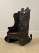 An early 20th century child's oak rocking chair, profusely carved all-over with floral motifs.