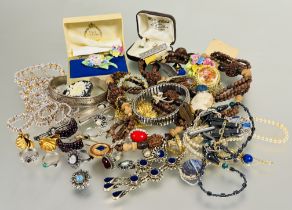 A collection of costume jewelry to include a carved bead necklace, gilt metal pendants and chains,