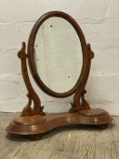 A large Victorian satin mahogany vanity mirror, the oval plate swivelling between two scrolling
