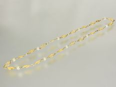 A continental yellow metal oval filigree link chain necklace with mounted with ten cultured pearl