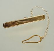 A modern 9ct gold tie clip with stamped border and safety chain and button loop L x 5.2cm 3.34g