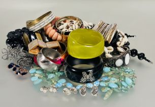 A box containing a large collection of stiff bangles, bracelets, cowrie shell necklace, a