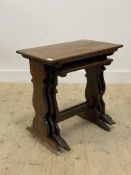 An early 20th century oak nest of three tables, each with rectangular top raised on shaped panel end