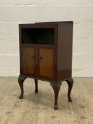 A Vintage mahogany and oak side cabinet, with an open shelf above two cupboard doors, raised on