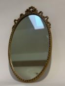 A 20thc gilt rococo style oval wall mirror with foliate scrolls to top. (52cmx31cm)