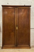 A late 19th century mahogany hall cupboard, the two panelled doors enclosing two brass sliding rails