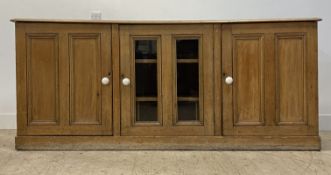 A Victorian pine sideboard / dresser base, fitted with a glazed cupboard door to centre, and flanked