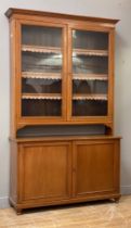 A late Victorian oak bookcase on cupboard, the projecting cornice above three adjustable shelves,