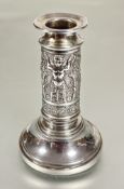 A continental white metal column single candle stick with chased central panel with alternating