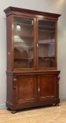 A Victorian mahogany bookcase on cupboard, the projecting cornice above two glazed doors enclosing a