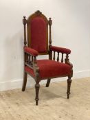 A late Victorian oak throne chair, with floral carved arched crest above an upholstered back, seat