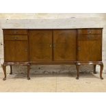 A 1950s walnut serpentine sideboard with arrangement of short drawers and panel doors raised on