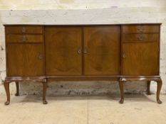 A 1950s walnut serpentine sideboard with arrangement of short drawers and panel doors raised on