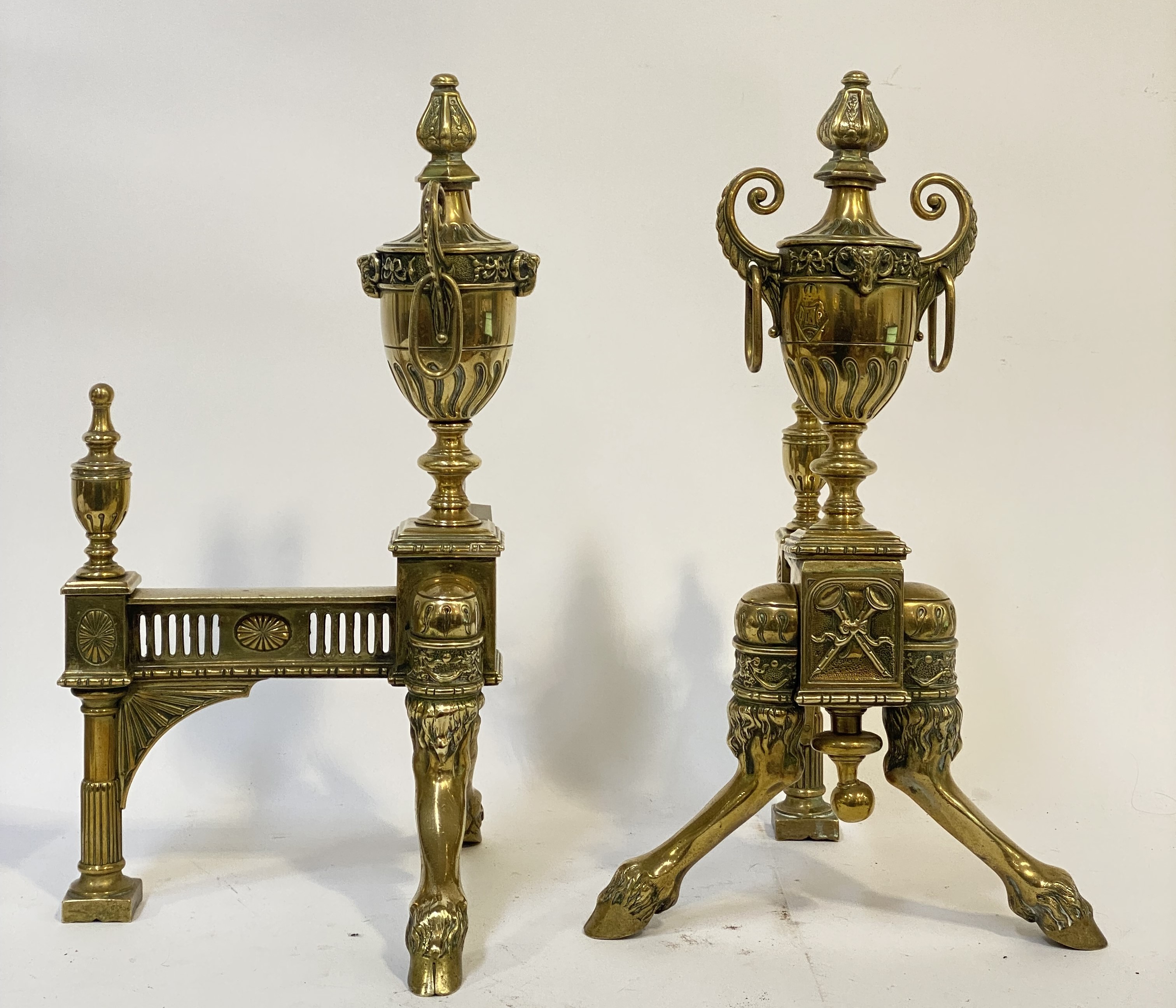 An ornate pair of cast brass fire place and-irons in the Neoclassical style, circa 1900, each with a