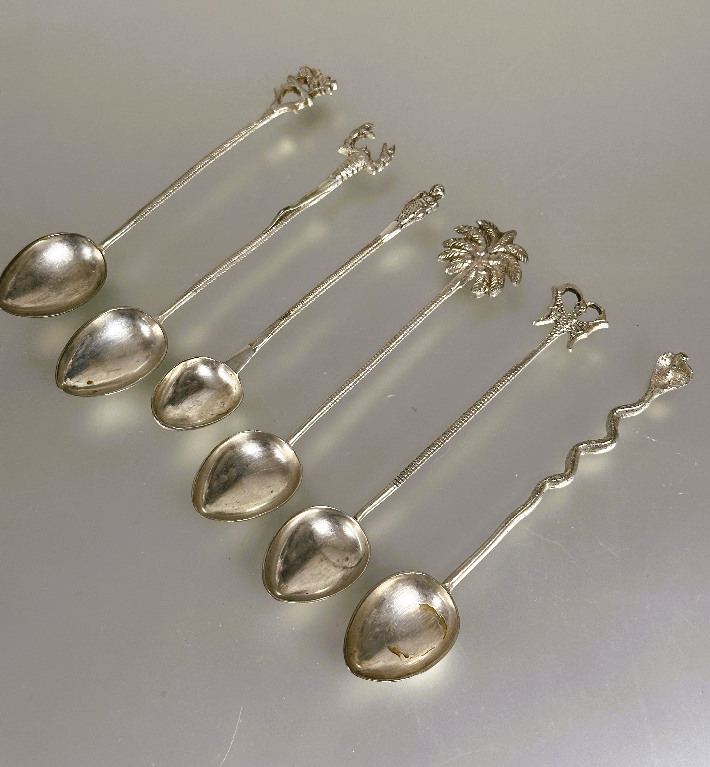 A set of six eastern white metal tea spoons each with different terminal including a palm tree,