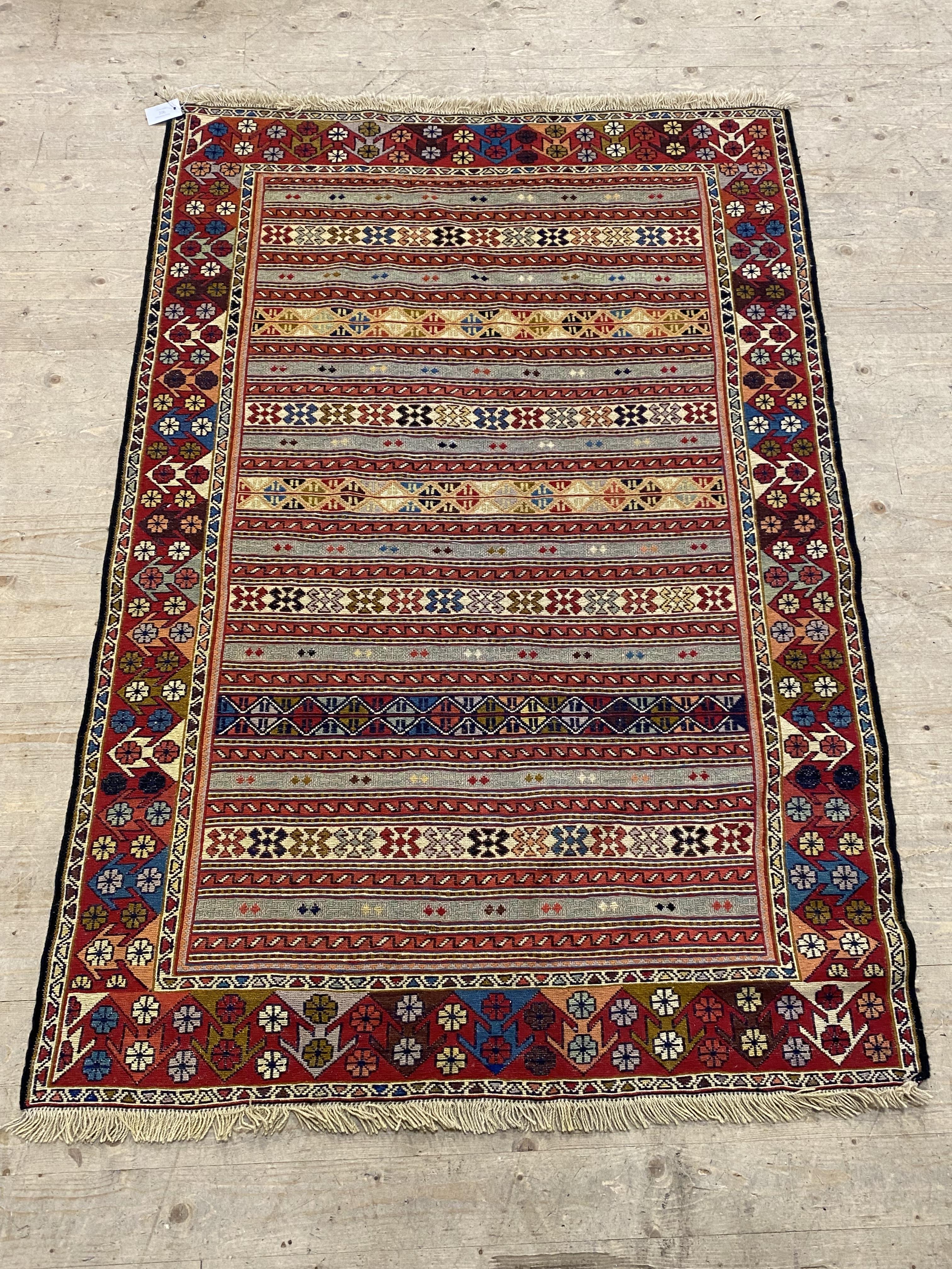 A hand knotted Soumak rug, brightly coloured and of lineal design. 126cm x 190cm.