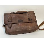 A leather light brown satchel with J.L.S initialled patch sewn to the front, with silver hardware