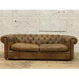 A traditional chesterfield sofa, upholstered in deep buttoned tan leather and crushed velvet sides