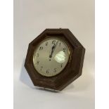 An early 20th century single train wall clock in an octagonal oak case, the silvered dial with
