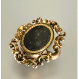 A Victorian yellow metal brooch with central revolving glazed oval panels enclosed within a rococo