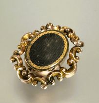 A Victorian yellow metal brooch with central revolving glazed oval panels enclosed within a rococo