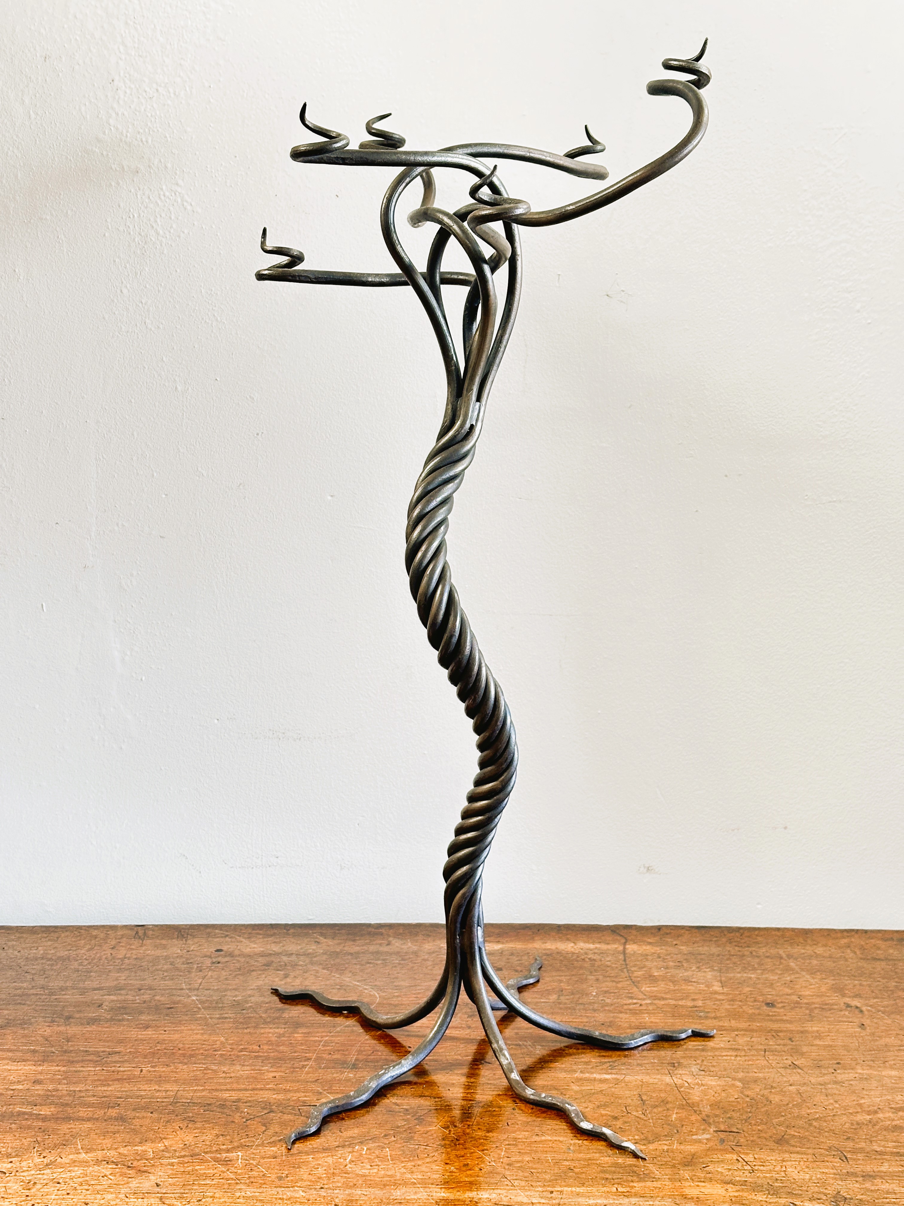 A modern wrought iron scrolling six branch candle stand of tree like design raised on five scrolling