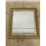 A floral moulded composition and parcel gilt wall hanging mirror. 60cm x 70cm.