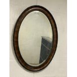 A 1920s oval walnut wall hanging mirror with ebonised beading to frame enclosing a bevelled plate