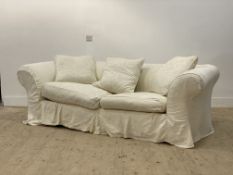 A large chesterfield sofa, with a loose fitted white cotton cover having embroidered floral