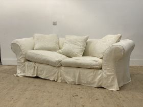 A large chesterfield sofa, with a loose fitted white cotton cover having embroidered floral