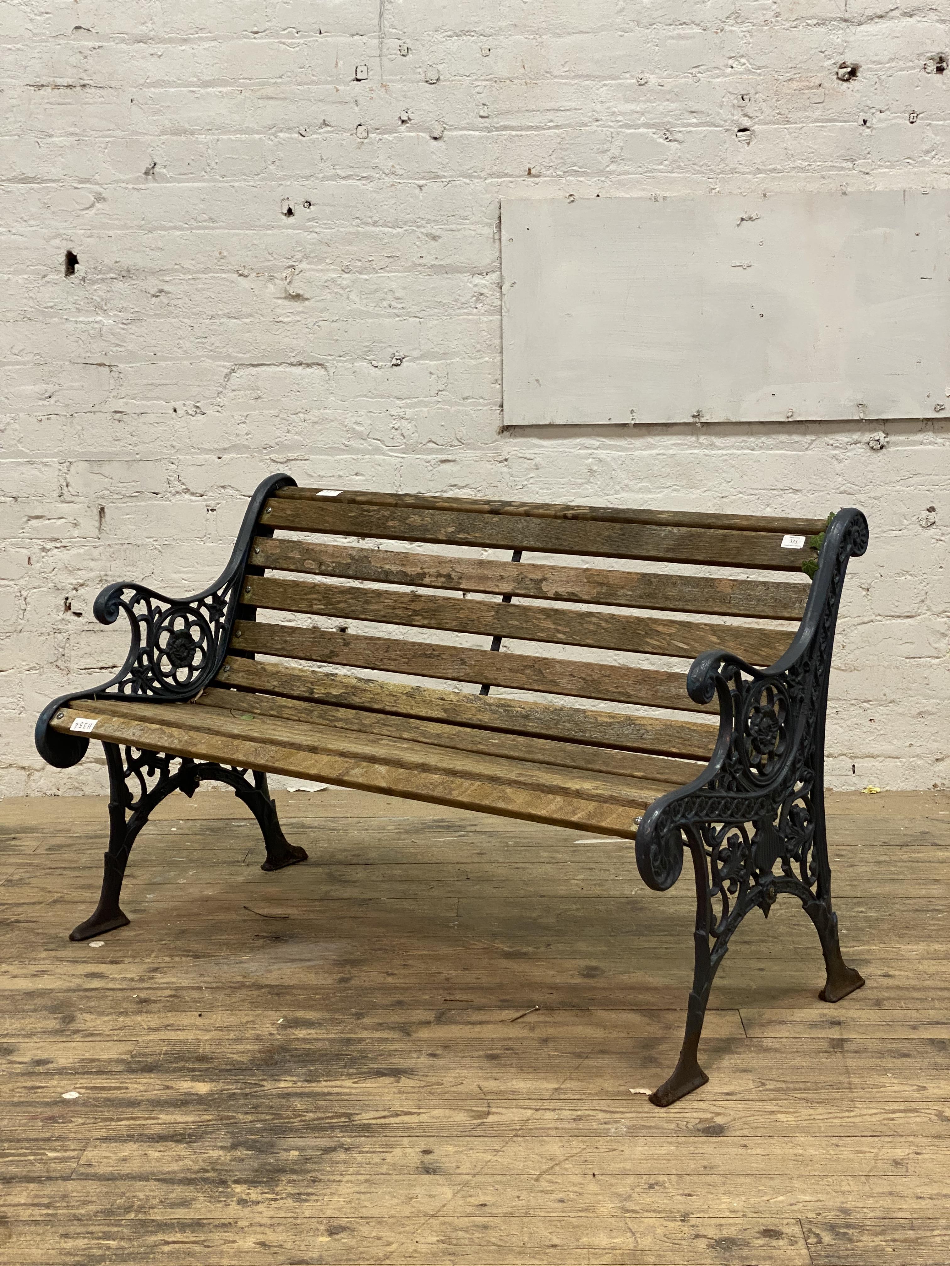 A cast metal and slatted teak three seat garden bench. L126cm.