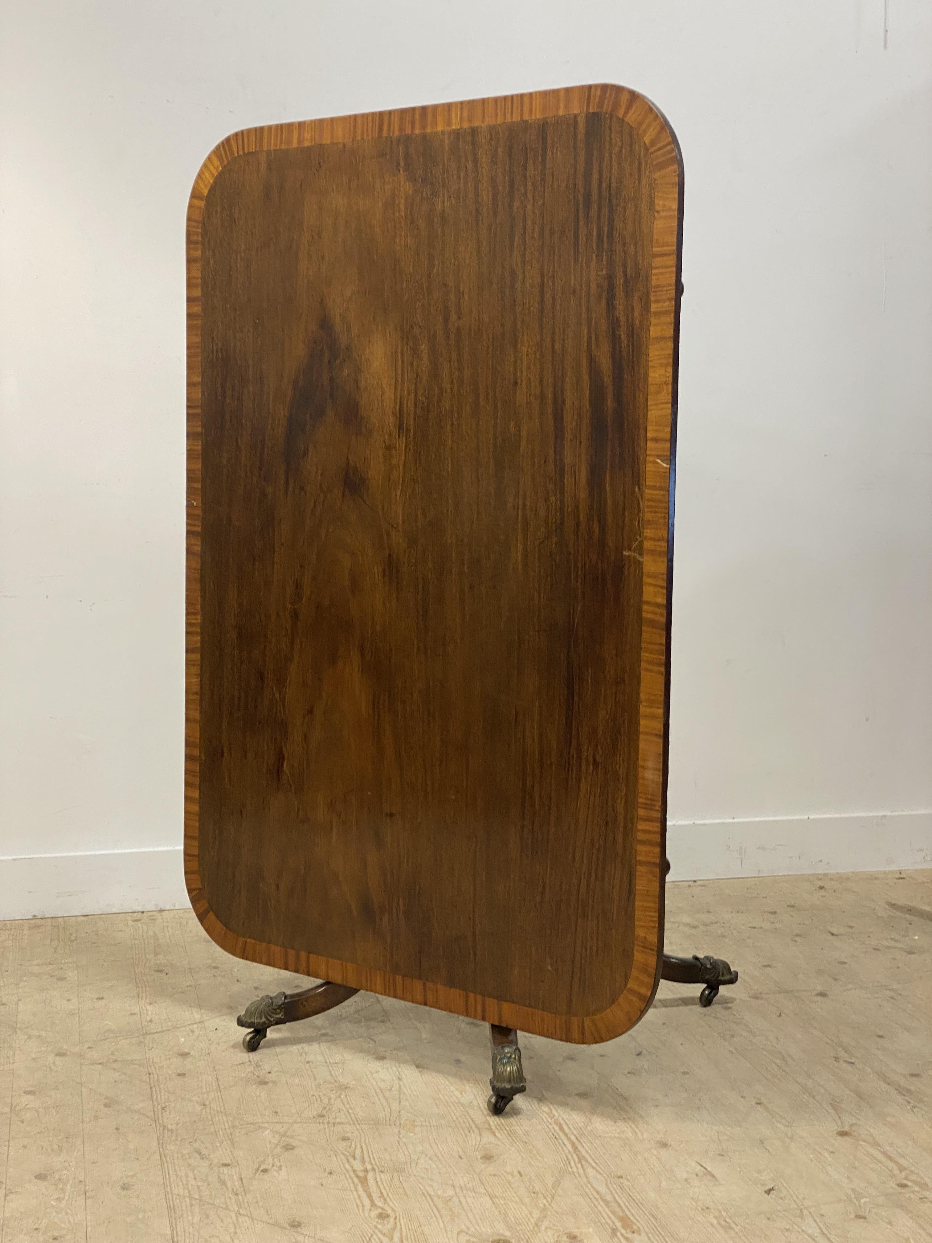 A Regency period mahogany breakfast table, the tilt top with deep satinwood cross band above four