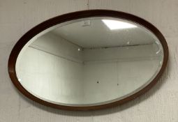 A mid-century teak oval framed wall mirror. 44cm x 72cm.
