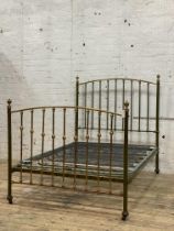 An Edwardian brass and green lacquered double bed frame, with urn finials, sprung base and moving on